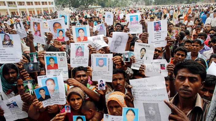 File picture shows relatives mourning as they show pictures of garment workers, who are believed to be trapped under the rubble of the collapsed Rana Plaza building, in Savar