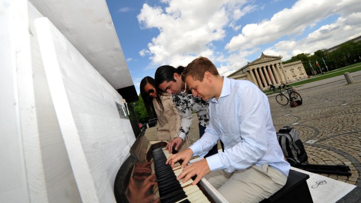 Spontane Live-Konzerte in München: Musik bringt Menschen zueinander, auch wenn es erst einmal drei sind, die sich an einem sonnigen Samstagmorgen am Königsplatz über das Klavier beugen.