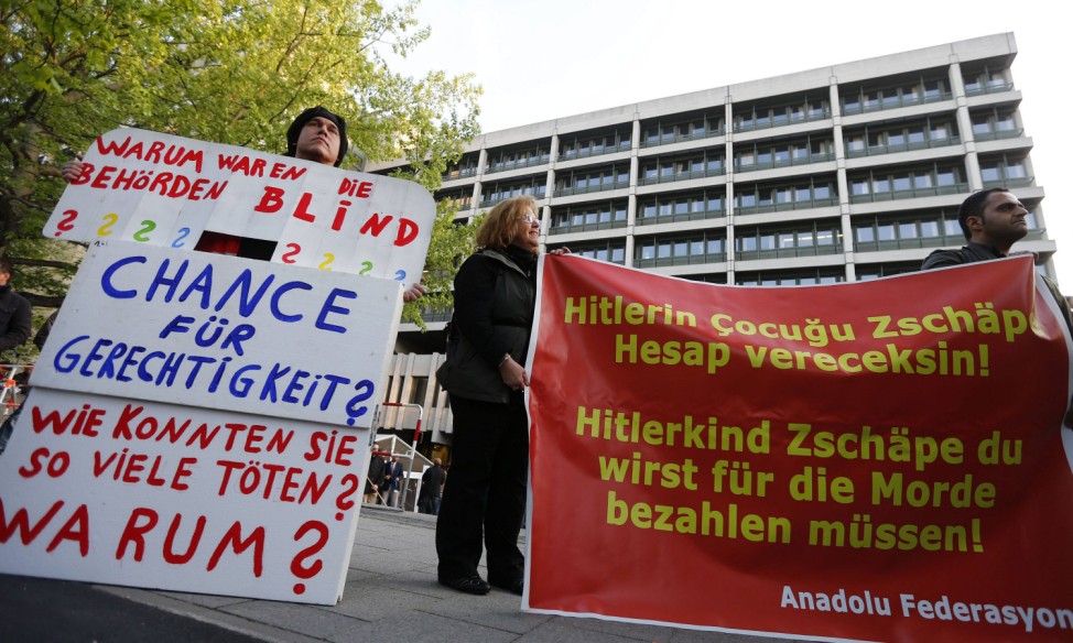 Protesters hold placards in front of a courthouse, where the trial against Zschaepe, a member of the neo-Nazi group NSU, will start later today, in Munich