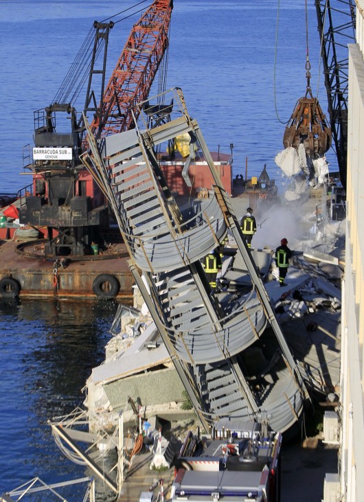 Firefighters stand near part of a collapsed control tower at Genoa's port