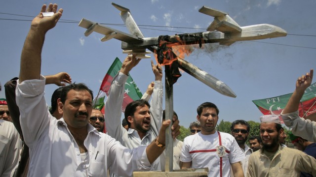 Activists of PTI hold up a burning mock drone aircraft during a rally against drone attacks in Peshawar