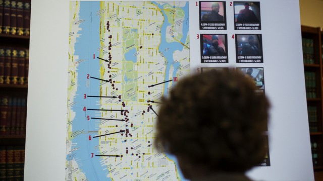 A woman looks at a map showing where eight members belonging to a New York-based cell of a global cyber criminal organization withdrew money from ATM machines, during a news conference in New York