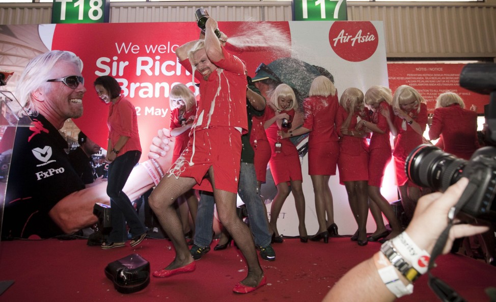 British entrepreneur Richard Branson, arrives at Kuala Lumpur dressed in an Air Asia flight attendant uniform and is doused in champagne by AirAsia's Chief Executive Tony Fernandes during an AirAsia promotional event