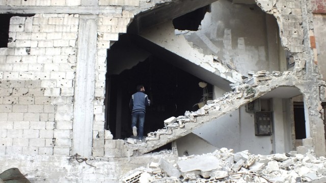 A man is seen on a damaged staircase in Homs