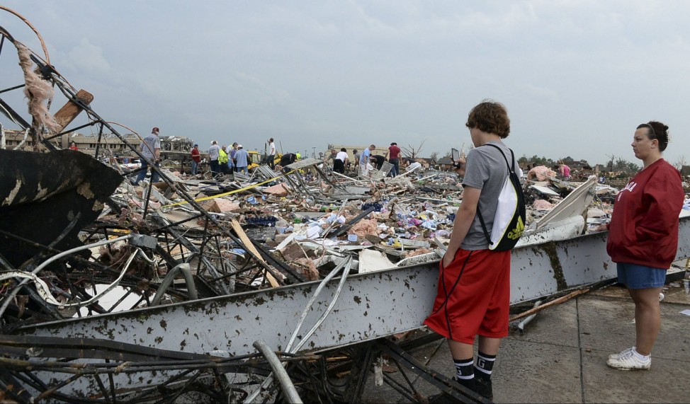 People watch as rescuers search through a convenience store that was destroyed after a tornado struck Moore, Oklahoma