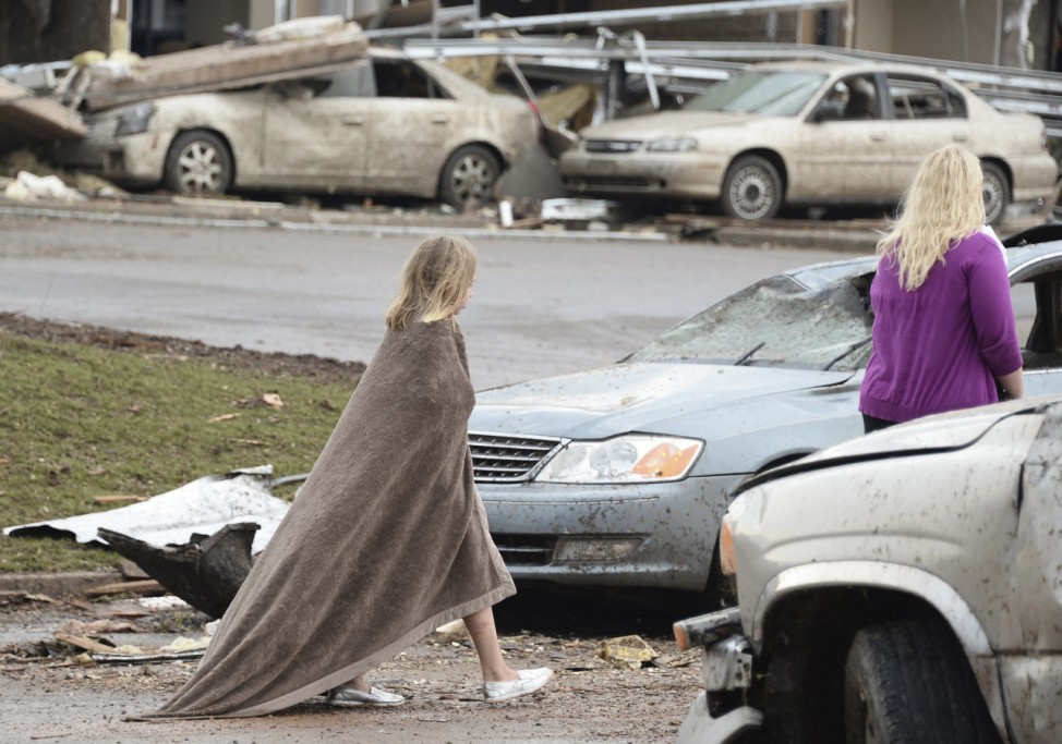 A girl walks, wrapped in a blanket, near the Moore Hospital after a tornado destroyed buildings and overturned cars in Moore