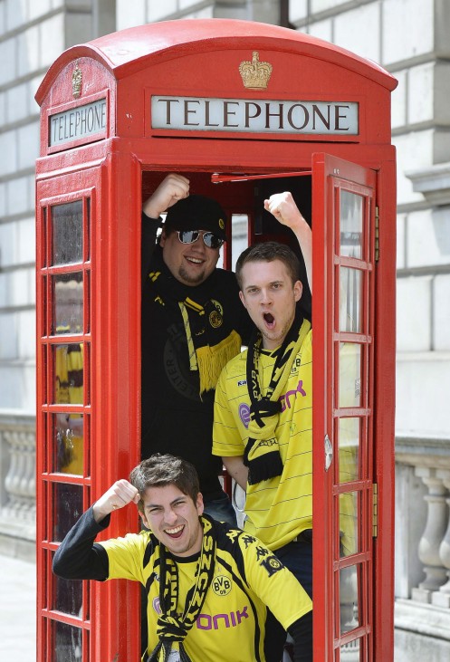 Borussia Dortmund supporters pose for photographs in a traditional red telephone box in central London