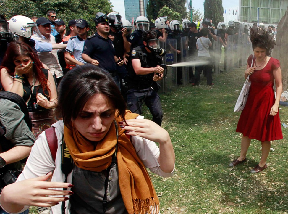 Turkish riot policeman uses tear gas during a protest in central Istanbul