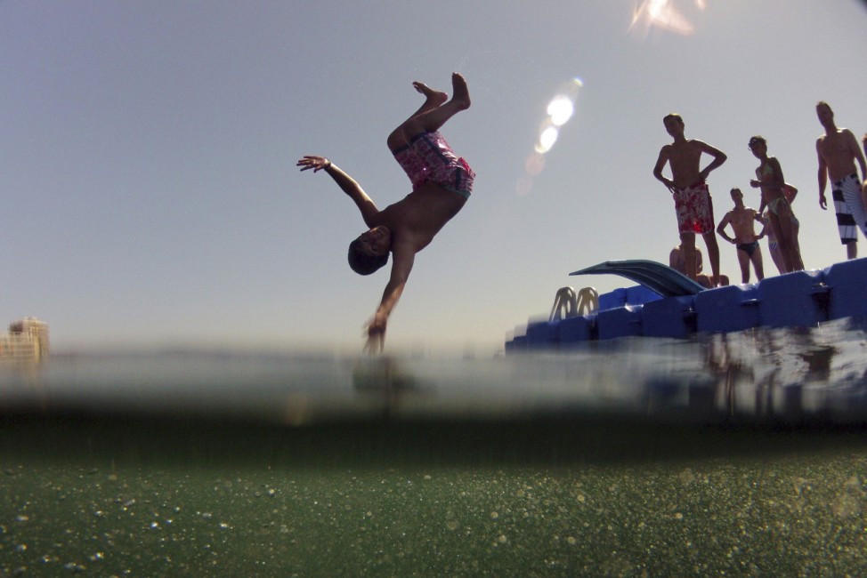 A boy dives into the water from a recreational platform at Magaluf beach, a popular tourist destination in Mallorca