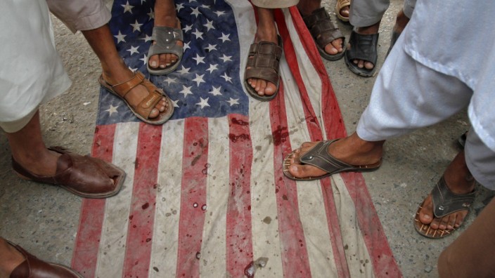 Men step on a U.S flag during an anti-American rally  organized by Shabab-e-Milli, the youth wing of the Jamaat-e-Islami party, in Peshawar
