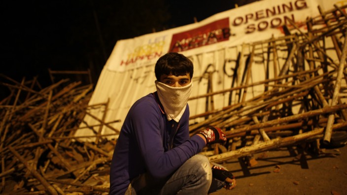 An anti-government protester squats behind barricades during an anti-government protest in Istanbul
