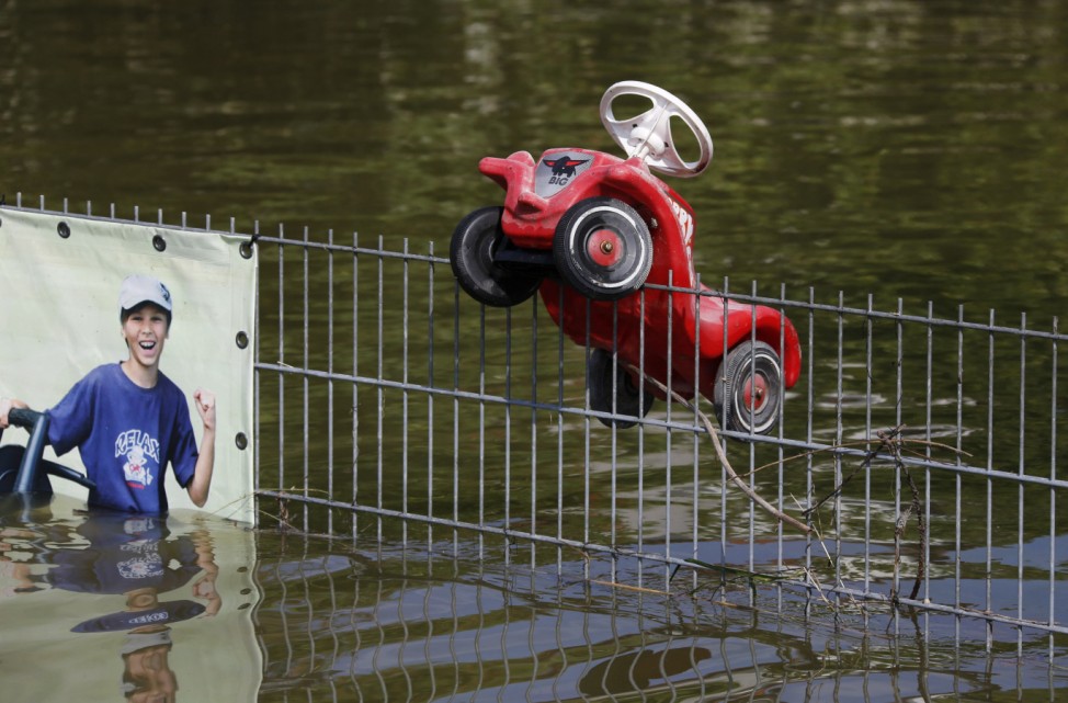 A toy vehicle hangs on a fence along a flooded street in Fischerdorf