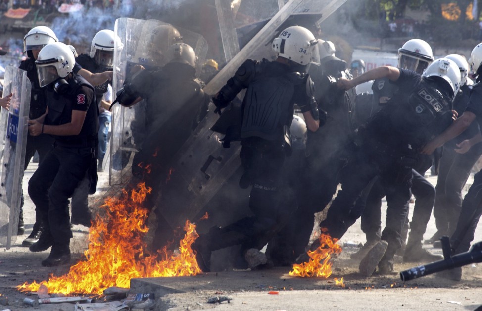 Turkish riot policemen are hit by petrol bombs during a protest at Taksim Square in Istanbul