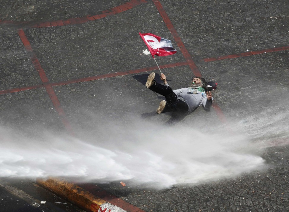 A protester falls as he is hit by a jet of water from a police water cannon during clashes in Istanbul's Taksim Square