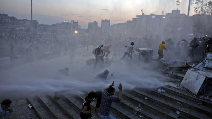 People run as riot police fires a water cannon on Gezi Park protesters at Taksim Square in Istanbul