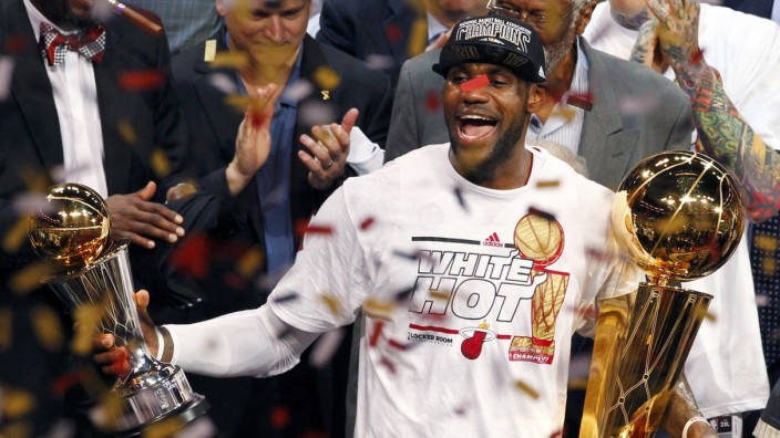 Miami Heat's James holds the Larry O'Brien Trophy and the Bill Russell MVP trophy after the Heat defeated the Spurs to win Game 7 of their NBA Finals basketball playoff in Miami