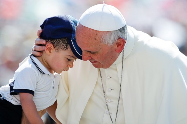 Pope Francis hugs a child as he arrives to lead the weekly audience in Saint Peter's Square at the Vatican