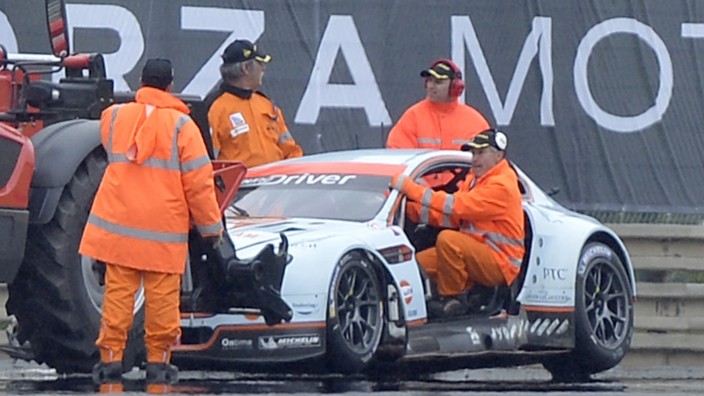 Security members work near the car of Denmark's Allan Simonsen during the Le Mans 24-hour sportscar race in Le Mans