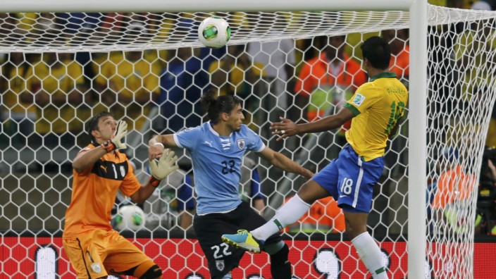 Brazil's Paulinho heads the ball to score a goal past Uruguay's Caceres and goalkeeper Muslera during their Confederations Cup semi-final soccer match at the Estadio Mineirao in Belo Horizonte