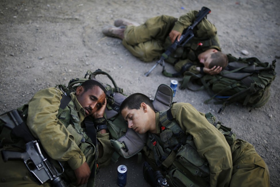 Israeli soldiers of the paratrooper brigade sleep as they take a break during a march near Jerusalem
