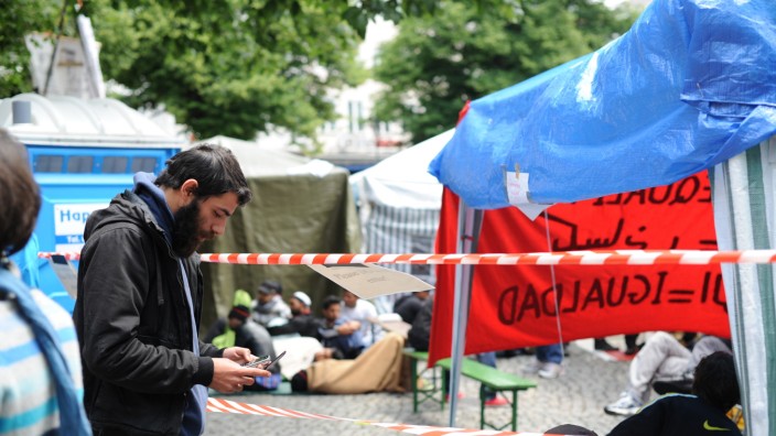 Hungerstreik der Flüchtlinge in München: Ein Mann steht neben dem Flüchtlingscamp am Rindermarkt und schaut auf sein Handy.