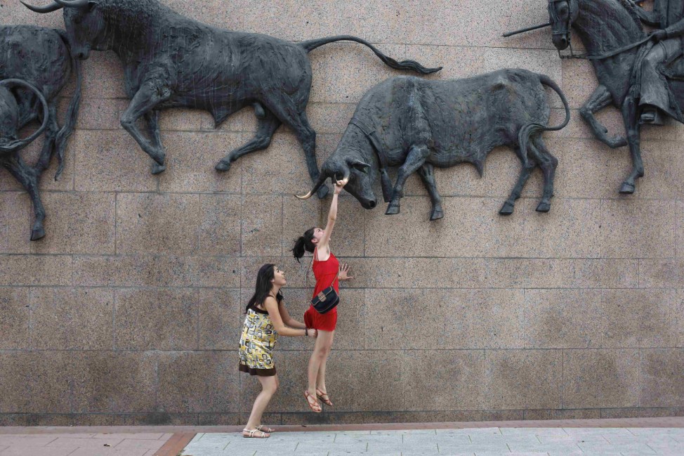 Woman tries to hang on bull sculpture outside Madrid's Las Ventas bullring
