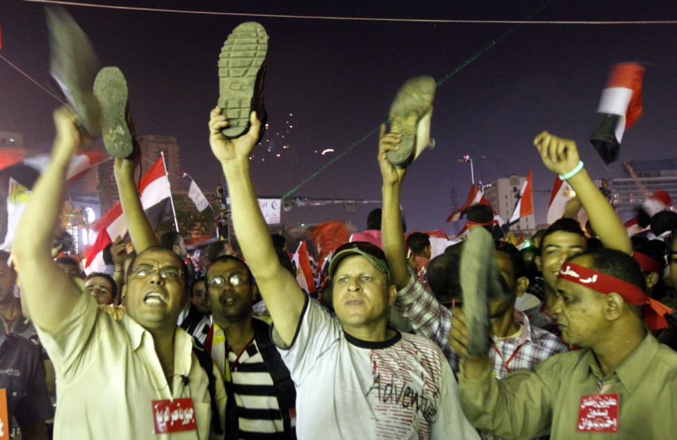 Anti-President Mohamed Mursi protesters hold up their shoes after a speech by Mursi, at Tahrir Square in Cairo