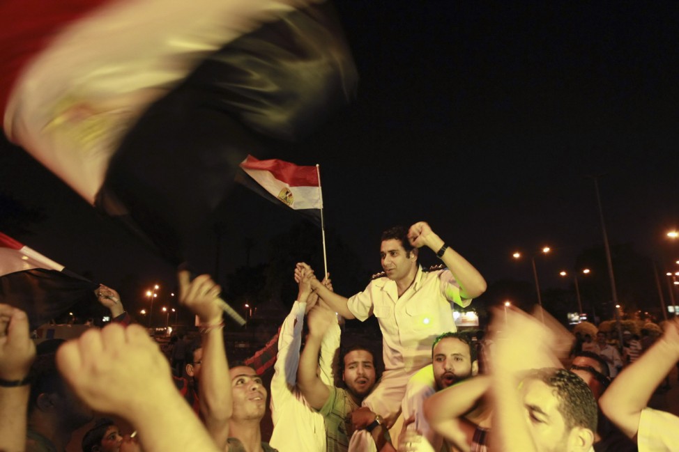 A policeman cheers with protesters, who are against Egyptian President Mohamed Mursi, as they dance and react in front of the Republican Guard headquarters in Cairo