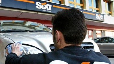 Deutsche Autovermieter: Sixt-Mitarbeiter reinigt an einer Zweigstelle in München einen Mietwagen: Das bisher an Wachstum gewohnte Unternehmen will nun auch einmal ein Auto weniger vermieten nach der Devise: höhere Preise, höherer Ertrag.