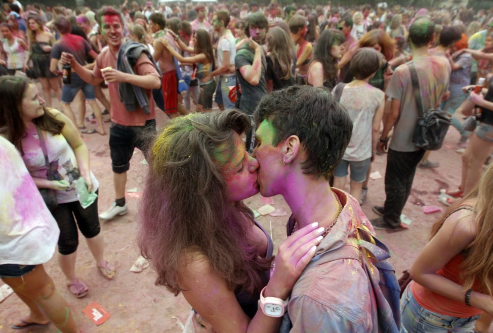 Participants kiss after throwing coloured powder during a recreation of the Holi festival of colours in Moscow