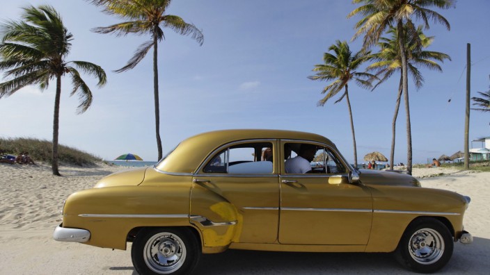 The driver of a U.S.-made car used as a private collective taxi drops people at a beach on the outskirts of Havana