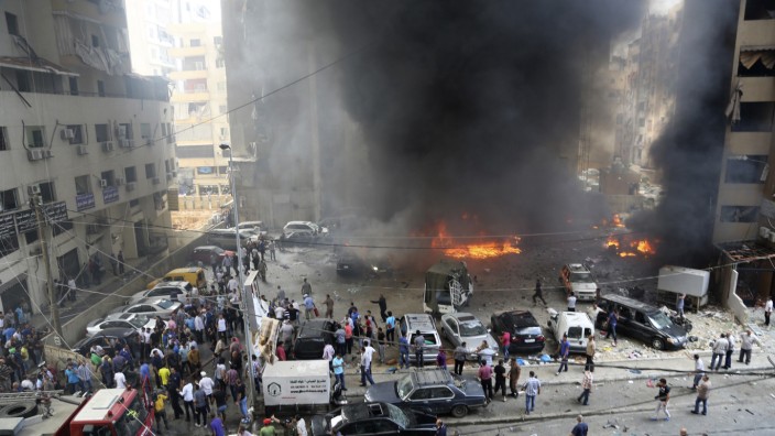 Civil Defence members, security personnel and civilians gather at the site of an explosion in Beirut's southern suburbs