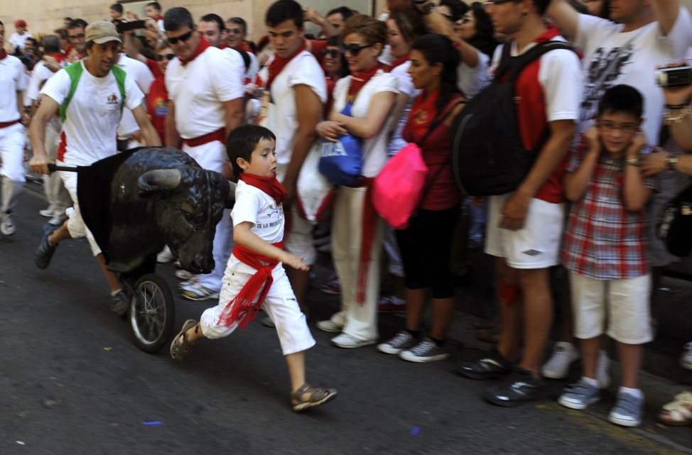 Boy runs in front of a toy bull during the Encierro Txiki on the fourth day of the San Fermin festival in Pamplona