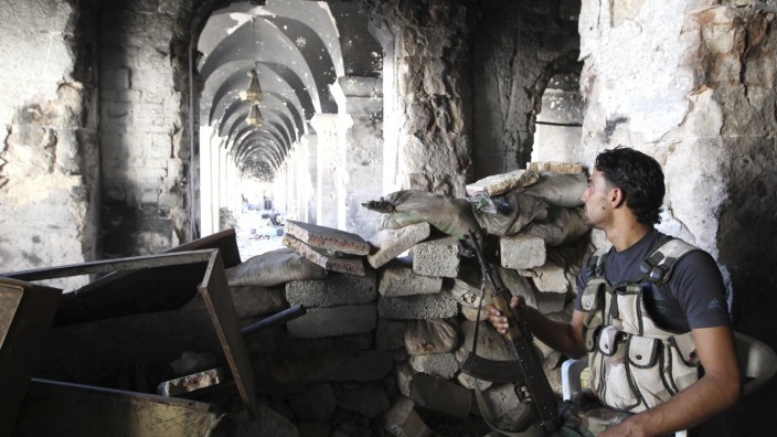 A Free Syrian Army fighter sits on a chair as he holds his weapon inside the Grand Umayyad mosque in Aleppo