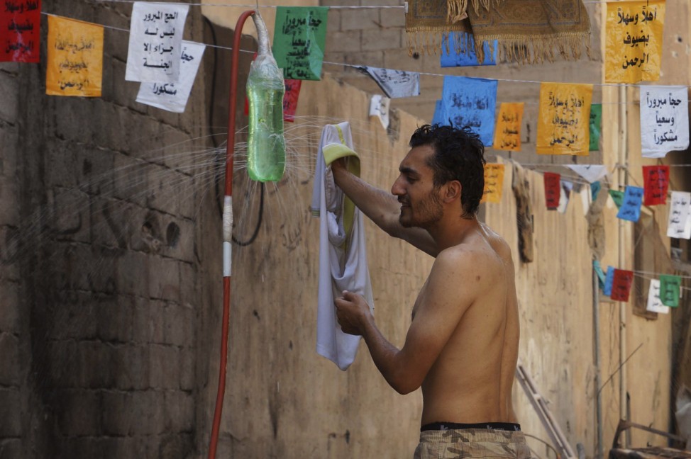 A Free Syrian Army fighter washes his shirt and cools himself with water to beat the heat  in Deir al-Zor