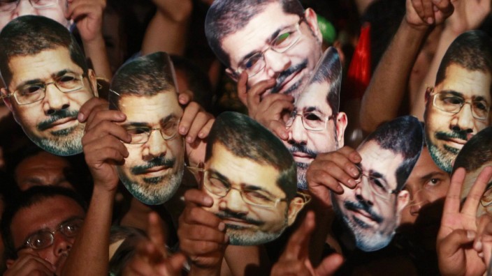 Members of the Muslim Brotherhood and supporters of deposed Egyptian President Mursi hold up masks of him as they gather at the Rabaa Adawiya square, in Cairo