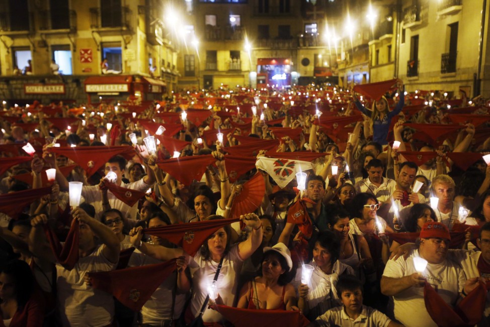 Revellers hold candles and red scarves during the closing ceremony of the San Fermin festival in Pamplona