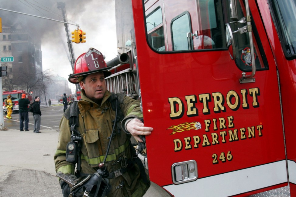 File photo of a Detroit firefighter getting gear from his fire truck as an abandoned building burns in downtown Detroit