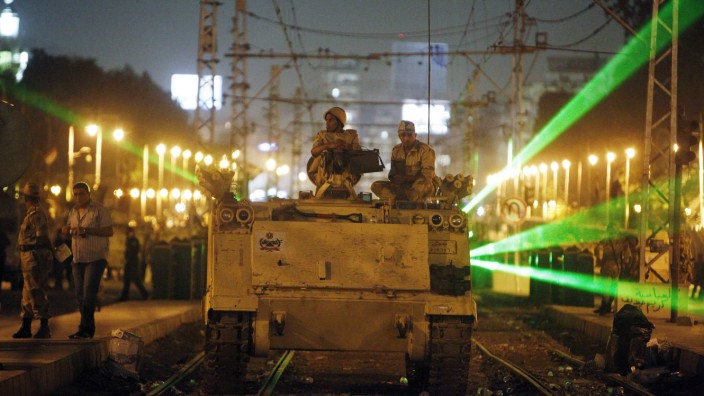 Egyptian Army soldiers sit on an APC on a tram track, during a patrol, as supporters of deposed president Mursi approach the presidential palace in Cair