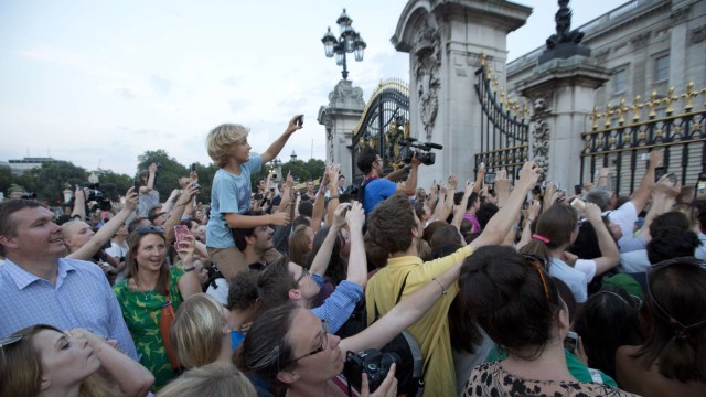 Crowds of people try to look at a notice formally announcing the birth of a son to Britain's Prince William and Catherine, Duchess of Cambridge, in the forecourt of Buckingham Palace, in central London