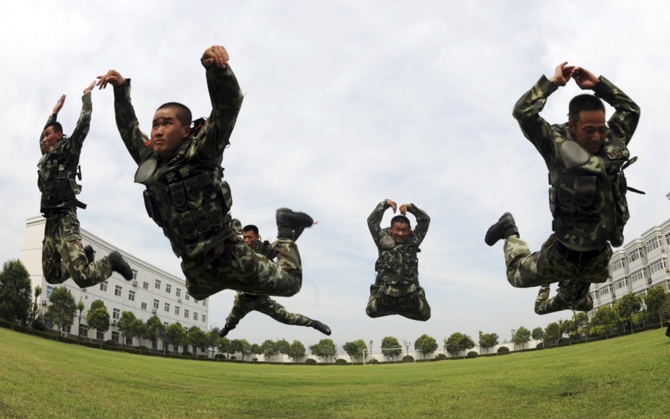 Paramilitary policemen jump as they practice during a summer drill in Bozhou
