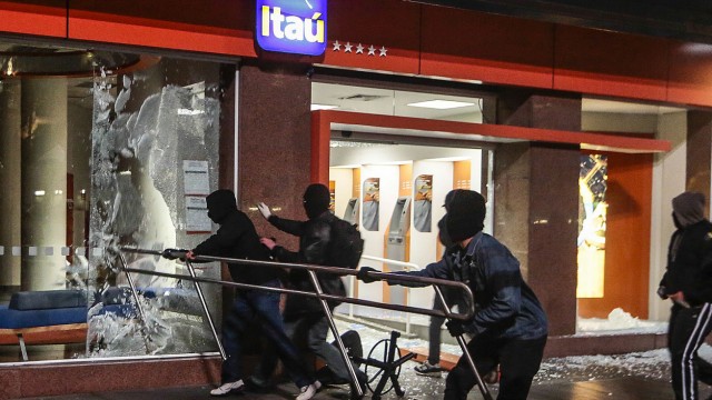 Demonstranten zerstören die Fensterscheibe einer Bankfiliale in São Paolo.
