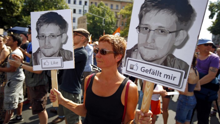 A protester carry two portraits of Snowden during a demonstration against secret monitoring programmes PRISM, TEMPORA, INDECT and showing solidarity with whistleblowers Snowden, Manning and others in Berlin