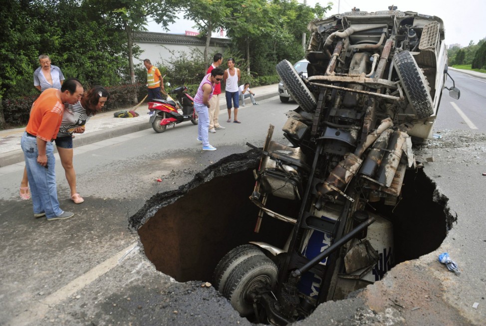 People look at a tanker after it fell into a caved-in area on a road in Xi'an