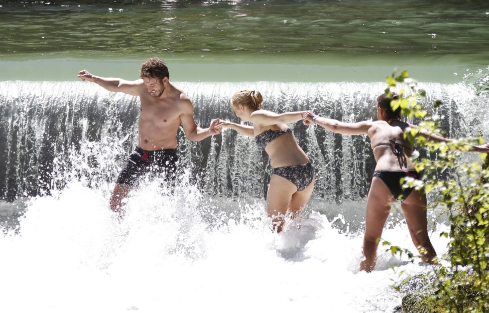 Ein Mann und zwei Frauen kühlen sich im Wasser ab.