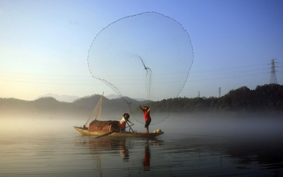 A fisherman casts his net to catch fish on Xin'an River in Jiande
