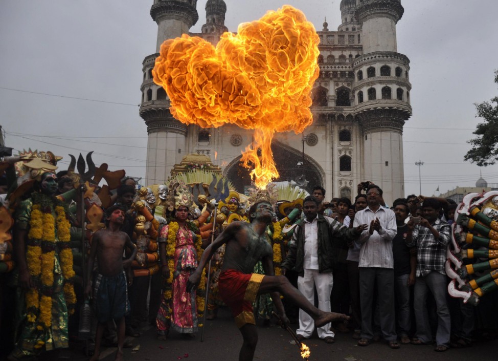 A performer blows fire from his mouth as he performs in front of the historical monument Charminar during the annual Hindu religious festival of Bonalu in Hyderabad