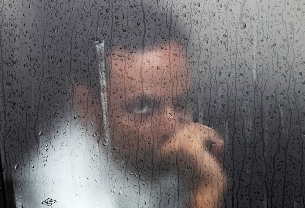A commuter watches through the window of a car during a rain shower in New Delhi