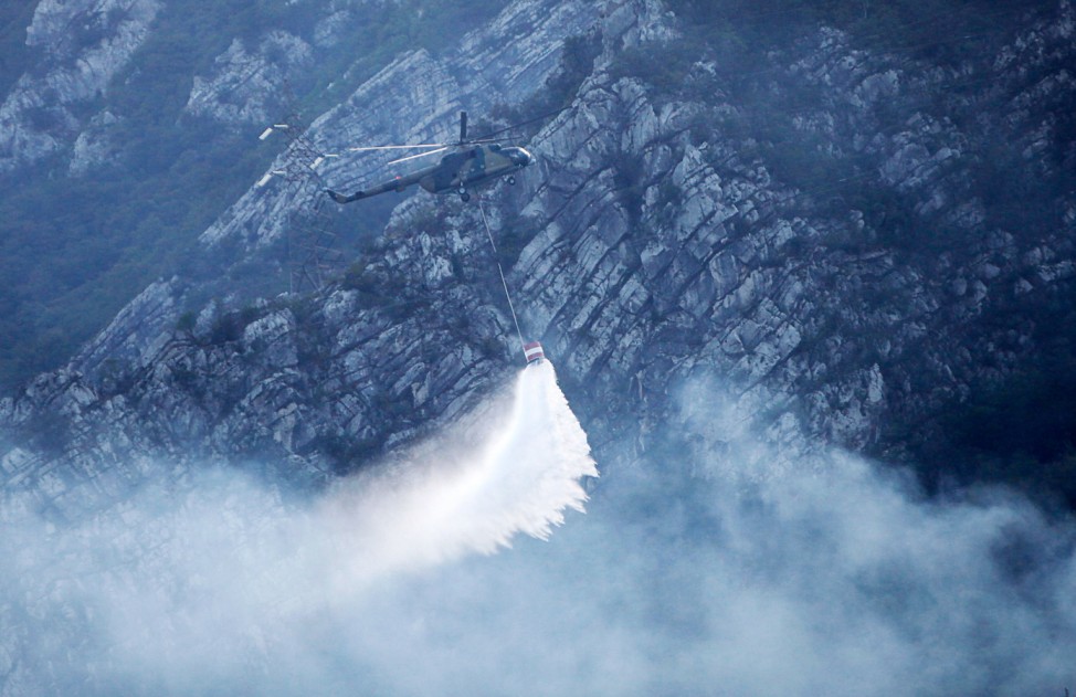 A helicopter drops water over a forest fire in Donja Jablanica