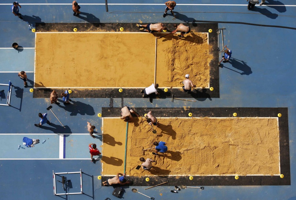 Volunteers prepare the sandpit for the 14th IAAF World Championships in Moscow
